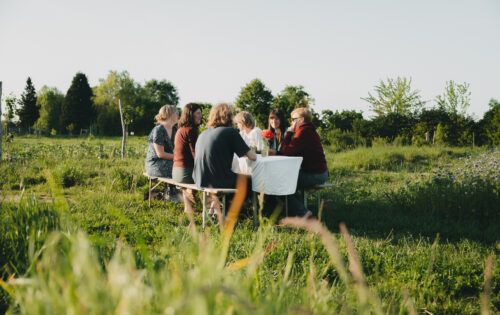 Menschen sitzen auf Bänken an einem Tisch und unterhalten sich