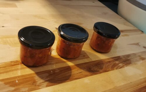 Zucchini-Salsa in kleinen Gläsern auf einem Holzbrett