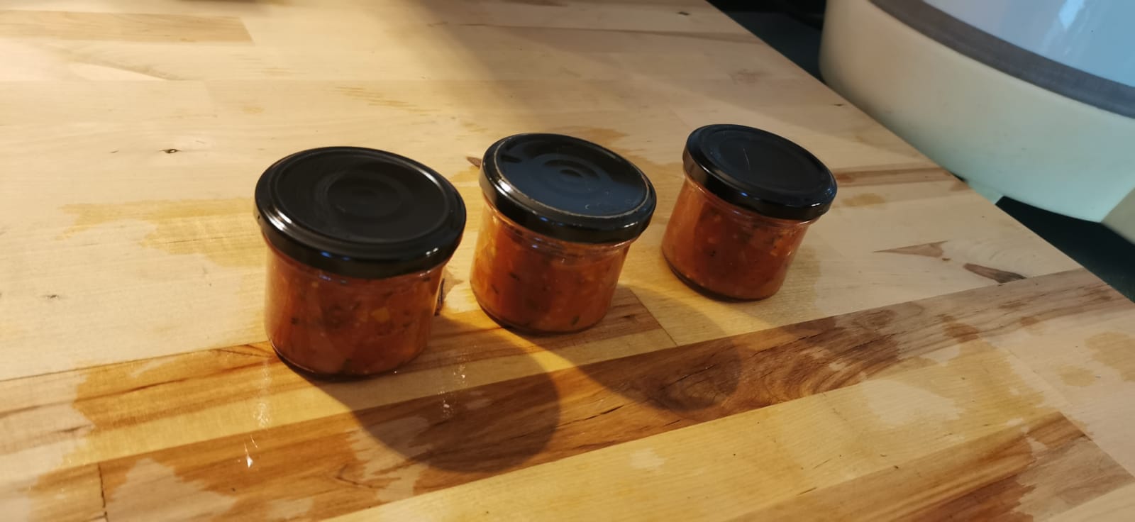 Zucchini-Salsa in kleinen Gläsern auf einem Holzbrett